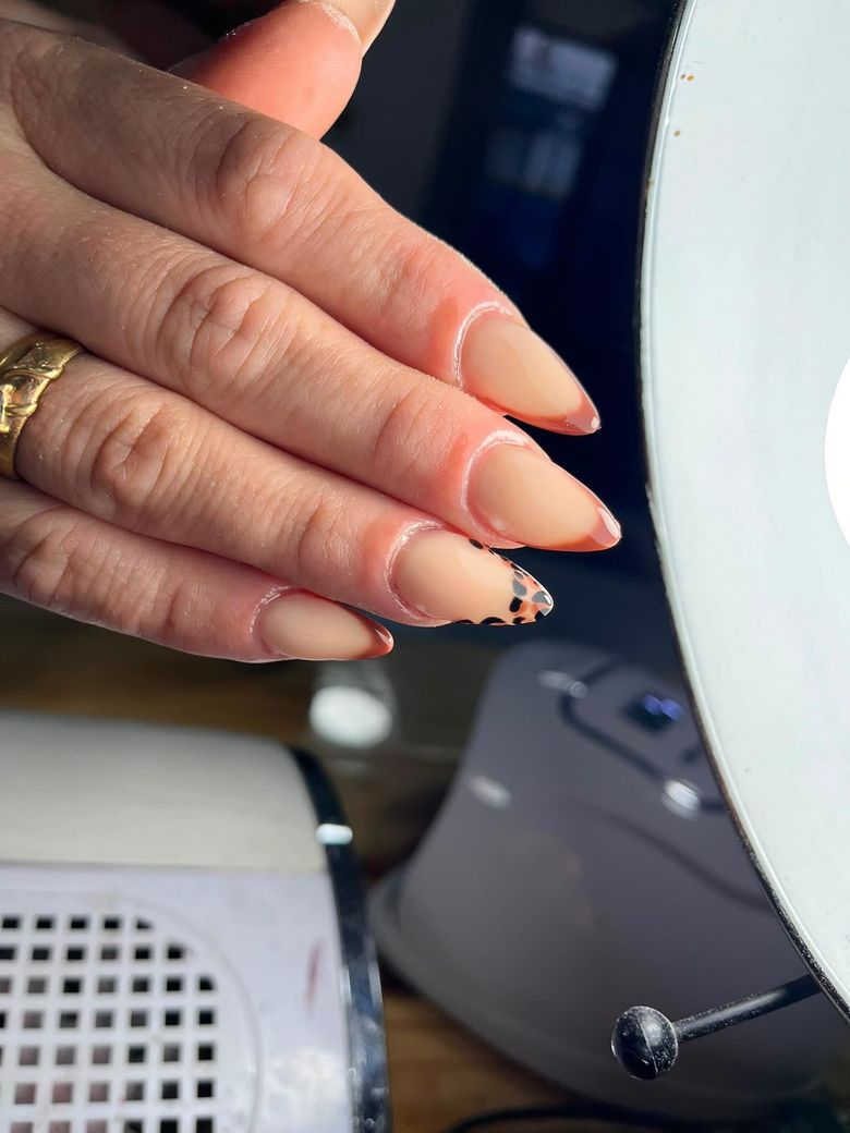 Uñas en tono durazno con french naranja y una con animal print